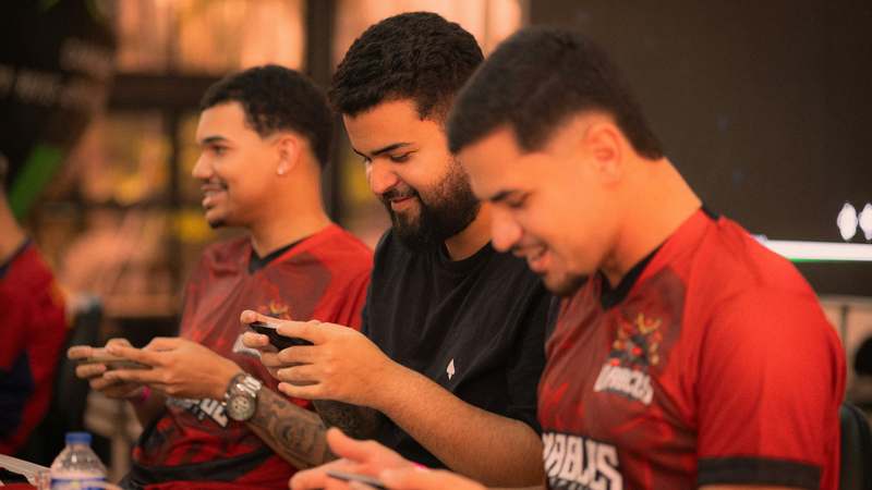 Pro gamers competing in a mobile esports tournament with phones and headsets, focused and intense